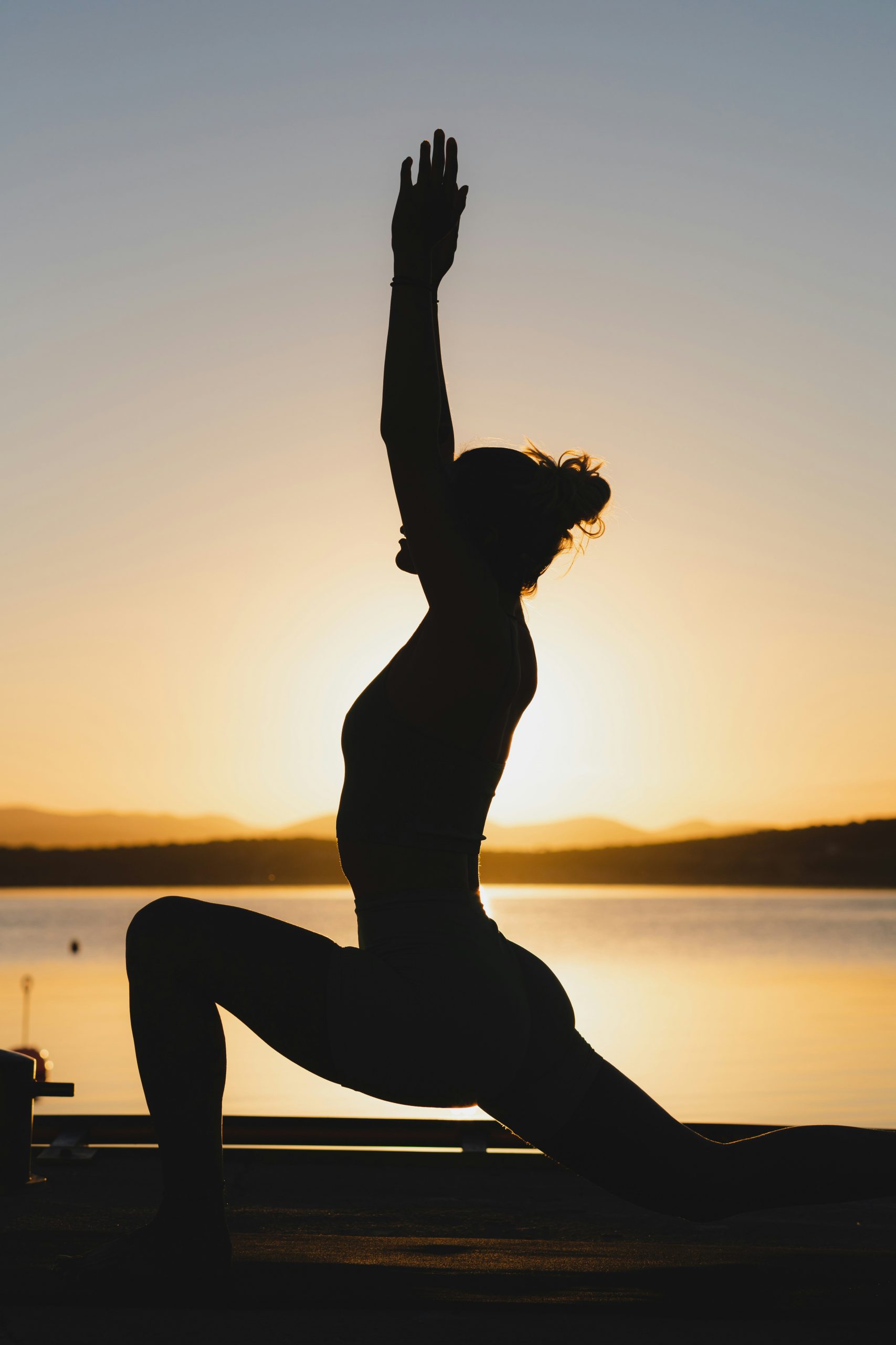 Woman practicing yoga beside the water